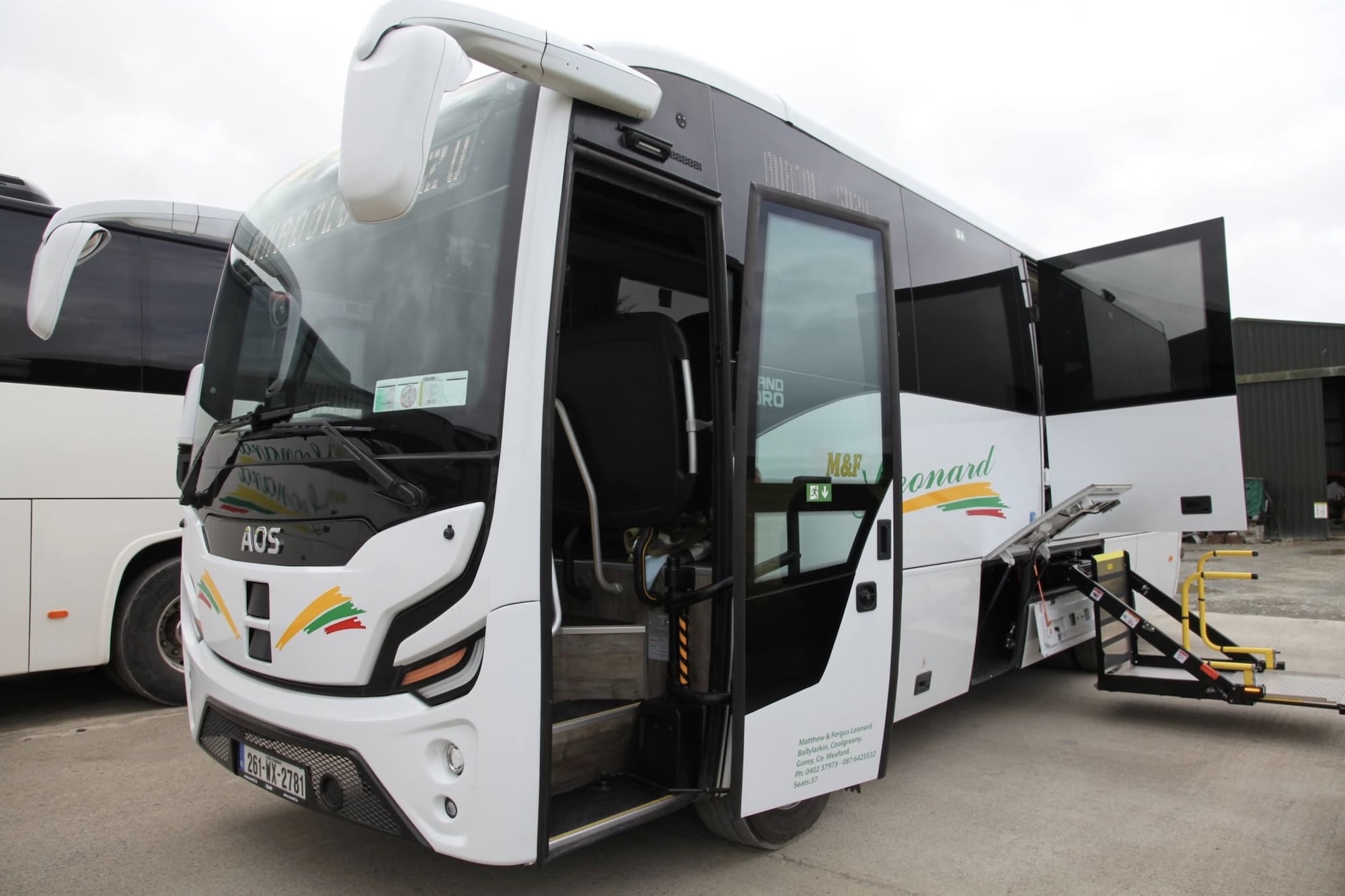 Wheelchair Accessible 2 White M&F Coach Hire bus with open door and ramp, "AOS" and "M&F Leonard" visible.